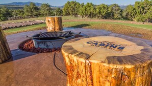 An outdoor barbecue area with a grill and a wooden stump labeled "Caban's." - Glamping Tent Single Queen - Royal Gorge Cabins (Cañon City)