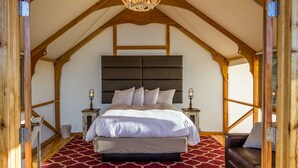 A bedroom with a large bed, a wooden ceiling, and a chandelier. - Glamping Tent Single Queen - Royal Gorge Cabins (Cañon City)