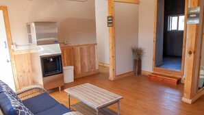 A cozy room with a sofa, a small table, a kitchenette, and a sign indicating the room is for men. - Glamping Tent Single Queen - Royal Gorge Cabins (Cañon City)
