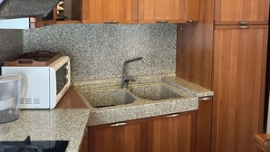 Una cocina con gabinetes de madera, encimera de granito, horno empotrado y cafetera.