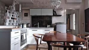 A modern kitchen with white cabinets, a built-in oven, and a dining table with wooden chairs. - Charming artist's hideaway with stunning view over Modica (modica)
