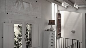 A hallway with a white door, a cabinet with drawers, a lamp, and a staircase with a metal railing. - Charming artist's hideaway with stunning view over Modica (modica)
