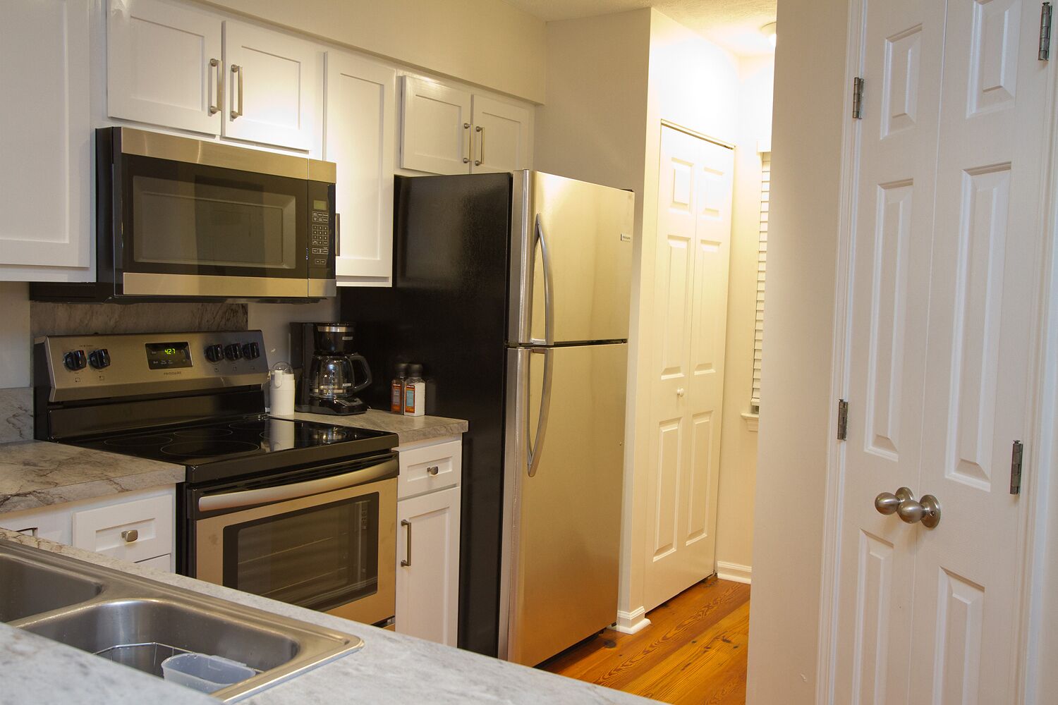 A kitchen with stainless steel appliances, a double sink, and white cabinetry.
