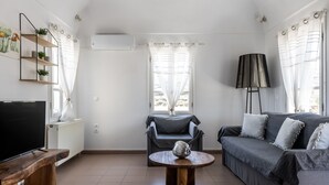 Ett vardagsrum med en TV, en soffa och ett soffbord med en dekorativ detalj.