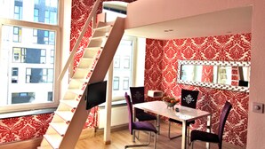 Une pièce dotée d’un escalier en colimaçon, d’une table à manger avec des chaises, d’un miroir et d’un papier peint à motifs.