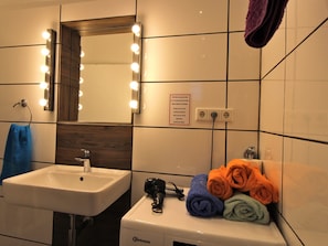 Une salle de bain équipée d’un lavabo, d’un miroir avec éclairage, d’un porte-serviettes et d’un panneau indicateur.
