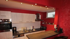 Une cuisine moderne dotée d’appareils électroménagers en acier inoxydable, de meubles en bois et d’un mur d’accent rouge.