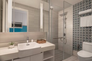Une salle de bain moderne avec une douche à parois de verre, un lavabo blanc et un miroir.