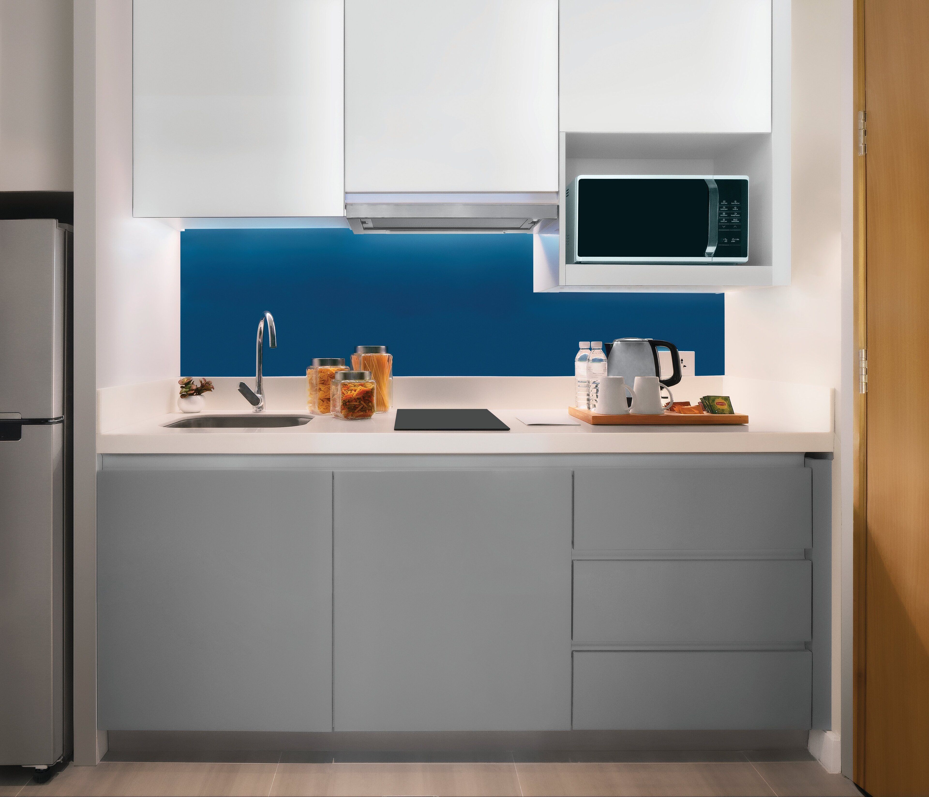 Una cocina moderna con un refrigerador de acero inoxidable, un microondas y un lavamanos.