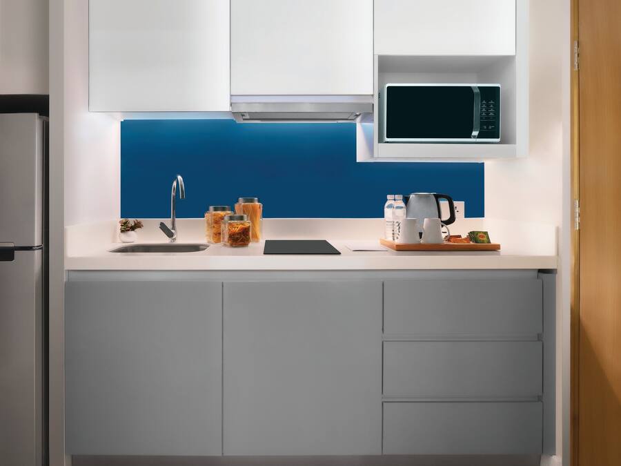 Una cocina moderna con un refrigerador de acero inoxidable, un microondas y un lavamanos.