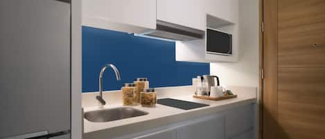 Una cocina moderna con un lavamanos doble, grifo de acero inoxidable y un salpicadero azul. Hay frascos de pasta y una cafetera en la encimera.