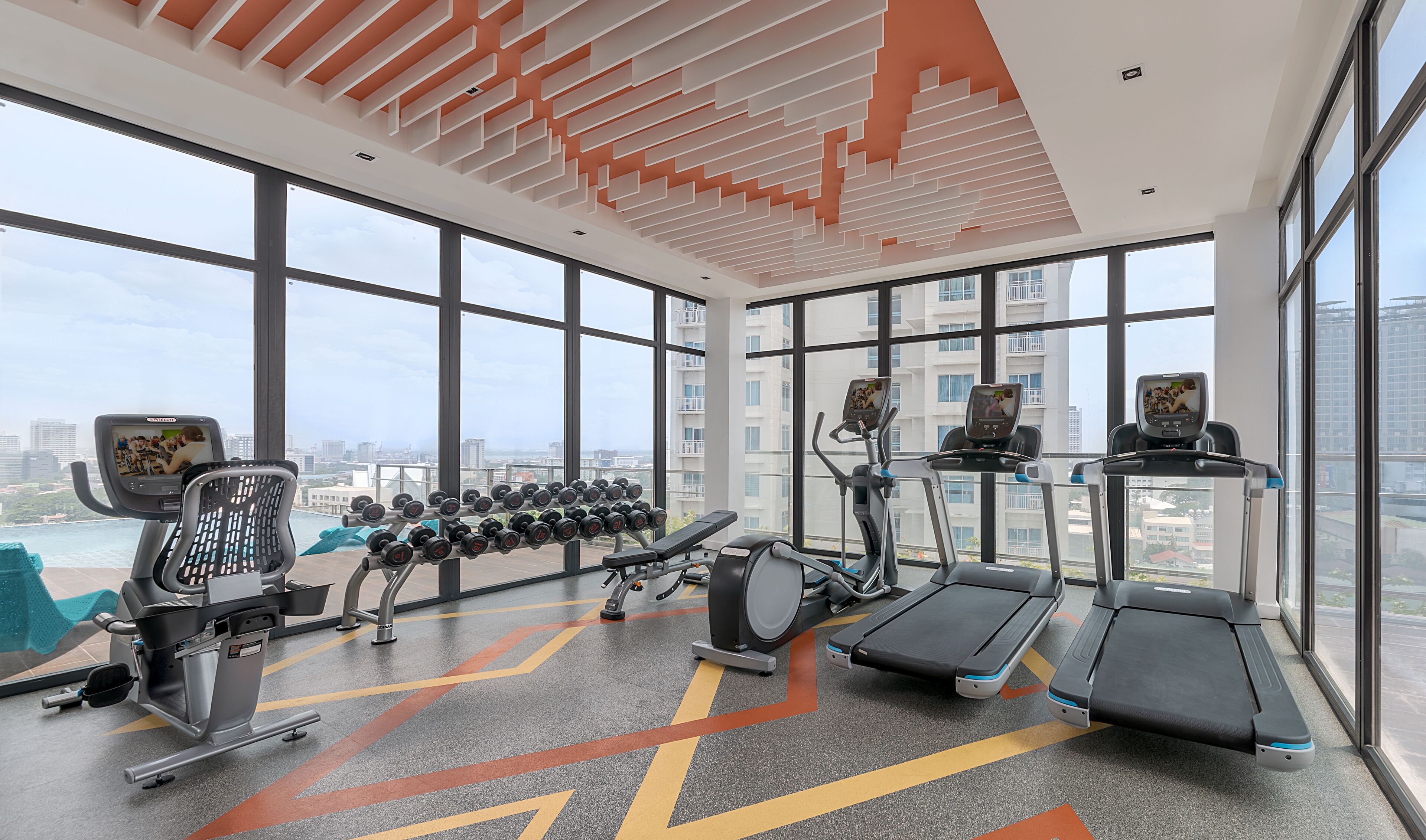 Ein Fitnessstudio mit Laufbändern, Crosstrainern und einer Hantelbank.