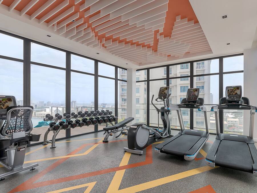 A gym with treadmills, elliptical machines, and a dumbbell rack.