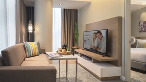 Una habitación de hotel moderna con sofá, una mesa de centro, televisor de pantalla plana y cama.