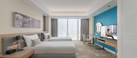 A modern hotel room with two beds, a desk, a chair, a large mirror, and a view of the outdoors.