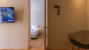 Et hotelværelse med en seng, et fjernsyn der viser et vejrkort og en dør, der fører til et andet rum.