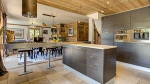 Une cuisine moderne dotée d’un îlot central, d’appareils électroménagers intégrés et d’un plafond au style rustique.