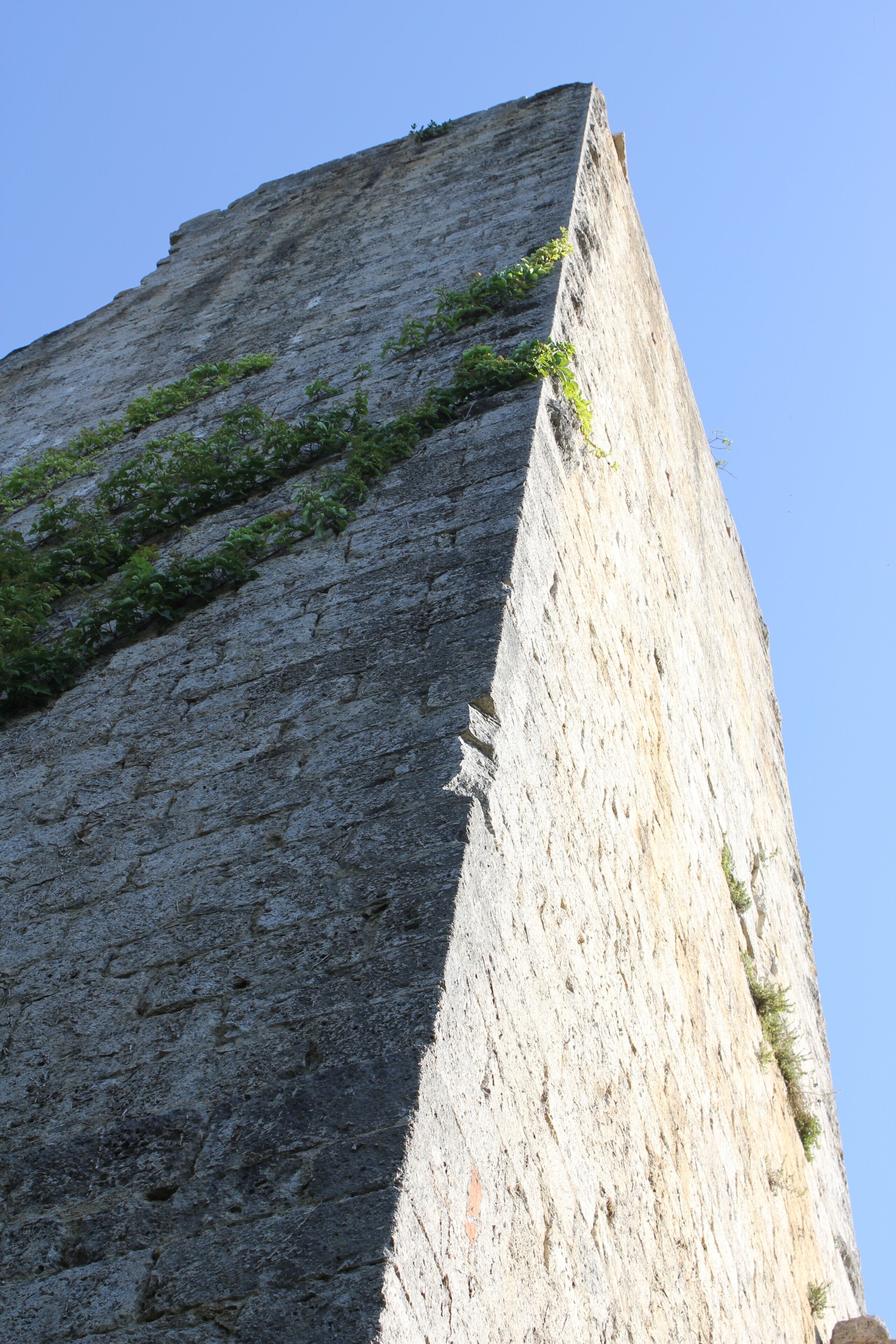 A tall, narrow stone structure with a clear sky in the background.