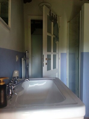A bathroom with a white sink, a mirror, and a door with frosted glass panels. - "Torre di Sant'Ansano" Farmhouse (Siena)