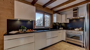 A modern kitchen with wooden beams, a large window, and stainless steel appliances.
