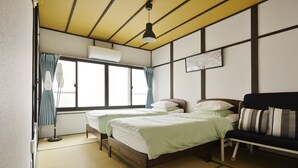 Une chambre avec deux lits, un canapé, un lampadaire et une fenêtre avec des rideaux.