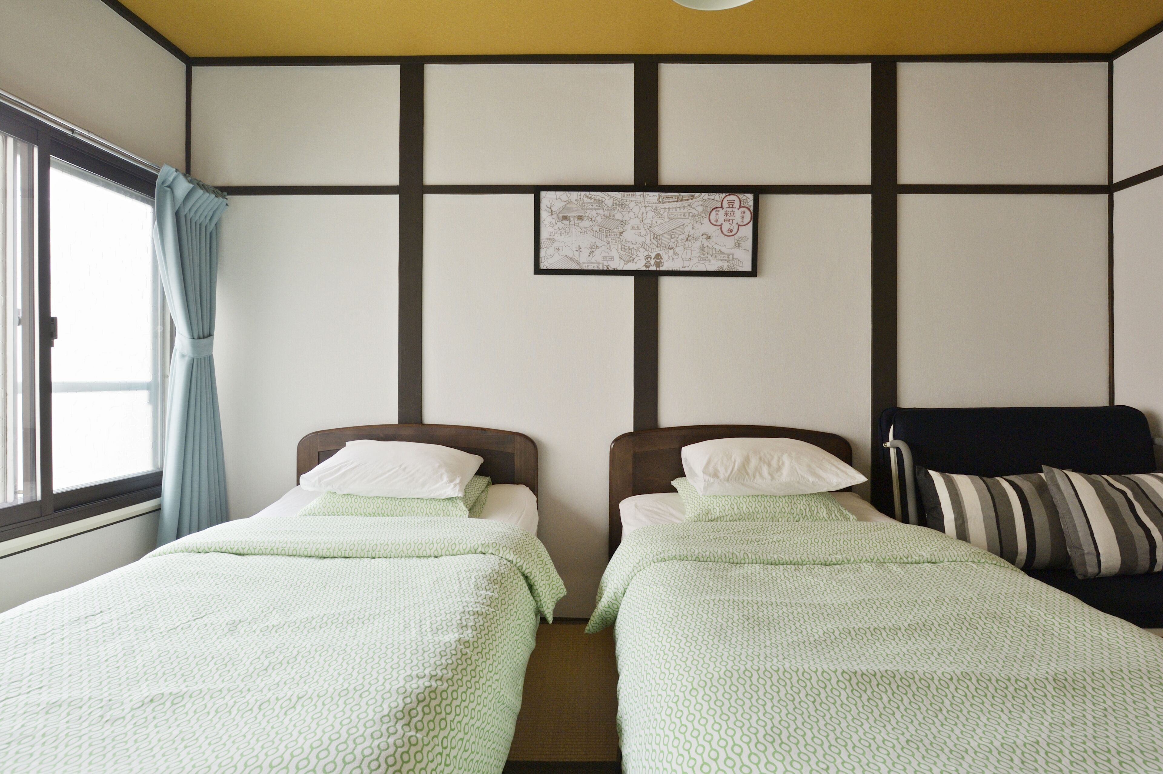 A room with two beds, a map on the wall, and a window with curtains.