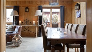 Interior de madeira com uma mesa de jantar, cadeiras e um candelabro.