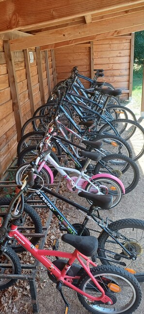 A row of bicycles parked against a wooden wall in a covered area.