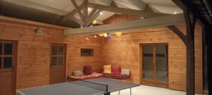 Una stanza in legno con un tavolo da ping pong, un divano con cuscini e una finestra.