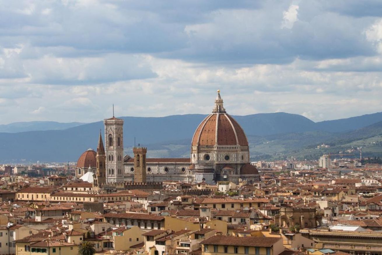 A panoramic view of a historic cityscape with prominent domed buildings and a tower.