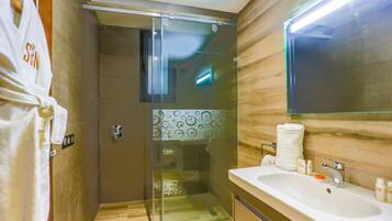 A modern bathroom with a glass-enclosed shower, a large mirror, and a white sink.