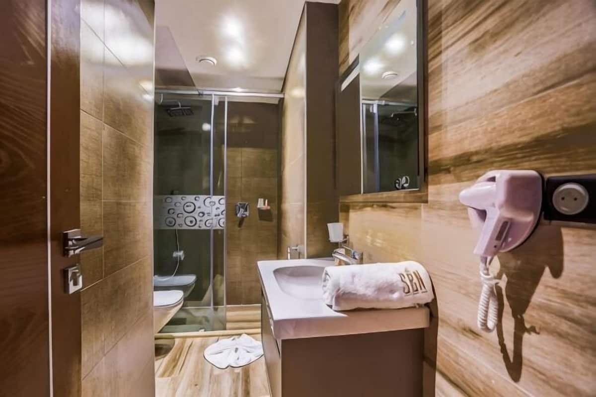 A modern bathroom with a glass shower enclosure, a wooden vanity, and a towel rack.