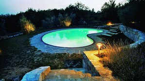 Una piscina de borde curvo, rodeada de escalones y un muro de piedra.
