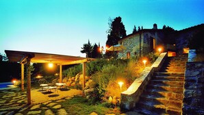 Una escalera de piedra que conduce a un edificio de piedra con un pérgola y zona de estar al aire libre.