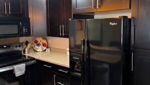 Una cocina moderna con armarios de madera oscura, un refrigerador negro, un microondas y una estufa.