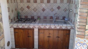 A compact kitchen with a gas stove, sink, and wooden cabinets. - Villa BUTTERFLY 1 SEA RELAX AND CLOSE TO CULTURAL SITES (Capaci)