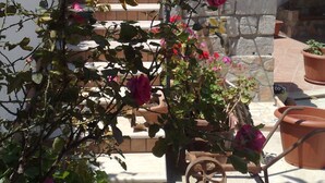 A garden with a bench, potted plants, and a stone wall. - Villa BUTTERFLY 1 SEA RELAX AND CLOSE TO CULTURAL SITES (Capaci)
