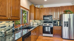 A modern kitchen with wooden cabinets, a stainless steel refrigerator, a built-in oven, and a microwave. - Short Walk to the Gondola Base (Steamboat Springs)