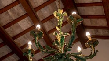 A chandelier with multiple candle-like lights, wooden beams, and a textured ceiling.