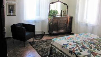 A bedroom with a bed, a dresser, a chair, and a window with curtains.