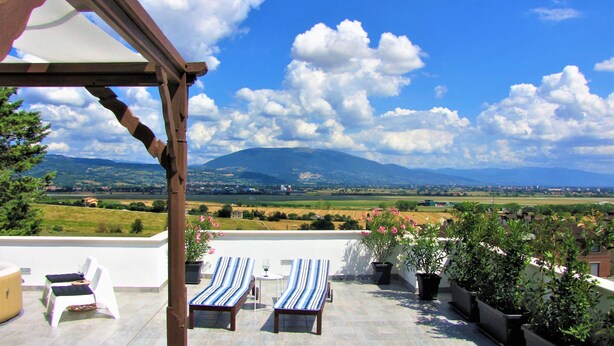 Una terraza con dos sillones de descanso, una mesa y plantas en macetas.