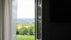 Una ventana con vistas a un paisaje verde, que incluye árboles y campos.
