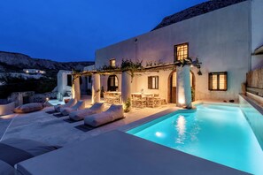 Area piscina con sedie a sdraio, tavolo da pranzo e piscina.
