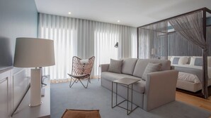 A modern living room with a sofa, armchair, and a small table. - Downtown Luxury Studio w/ Balcony by Liiiving (Porto)