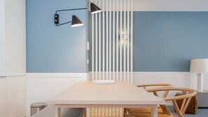 A modern dining area with a wooden table, benches, and a white partition with vertical slats. - Downtown Luxury Studio w/ Balcony by Liiiving (Porto)