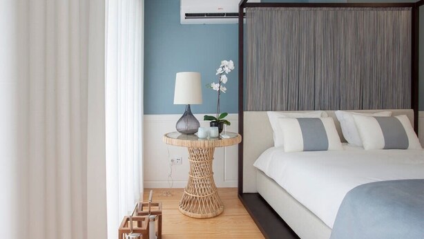 A bedroom with a bed, a round table with a lamp, and a potted plant. - Downtown Luxury Studio w/ Balcony by Liiiving (Porto)