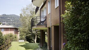 Un bâtiment à deux étages doté d’un balcon, d’une cour verdoyante et d’un banc.