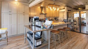 Una cocina moderna con electrodomésticos de acero inoxidable, piso de madera y una zona de bar con taburetes.