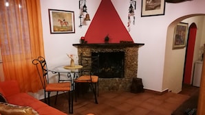 Ein Wohnzimmer mit Kamin, orangefarbener Möbel und unterschiedlichen Wanddekorationen.