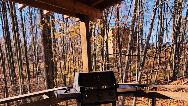 A hot tub with a wooden deck and a grill in the background. - Wild and Wonderful Wilderness Cabin! (Hico)